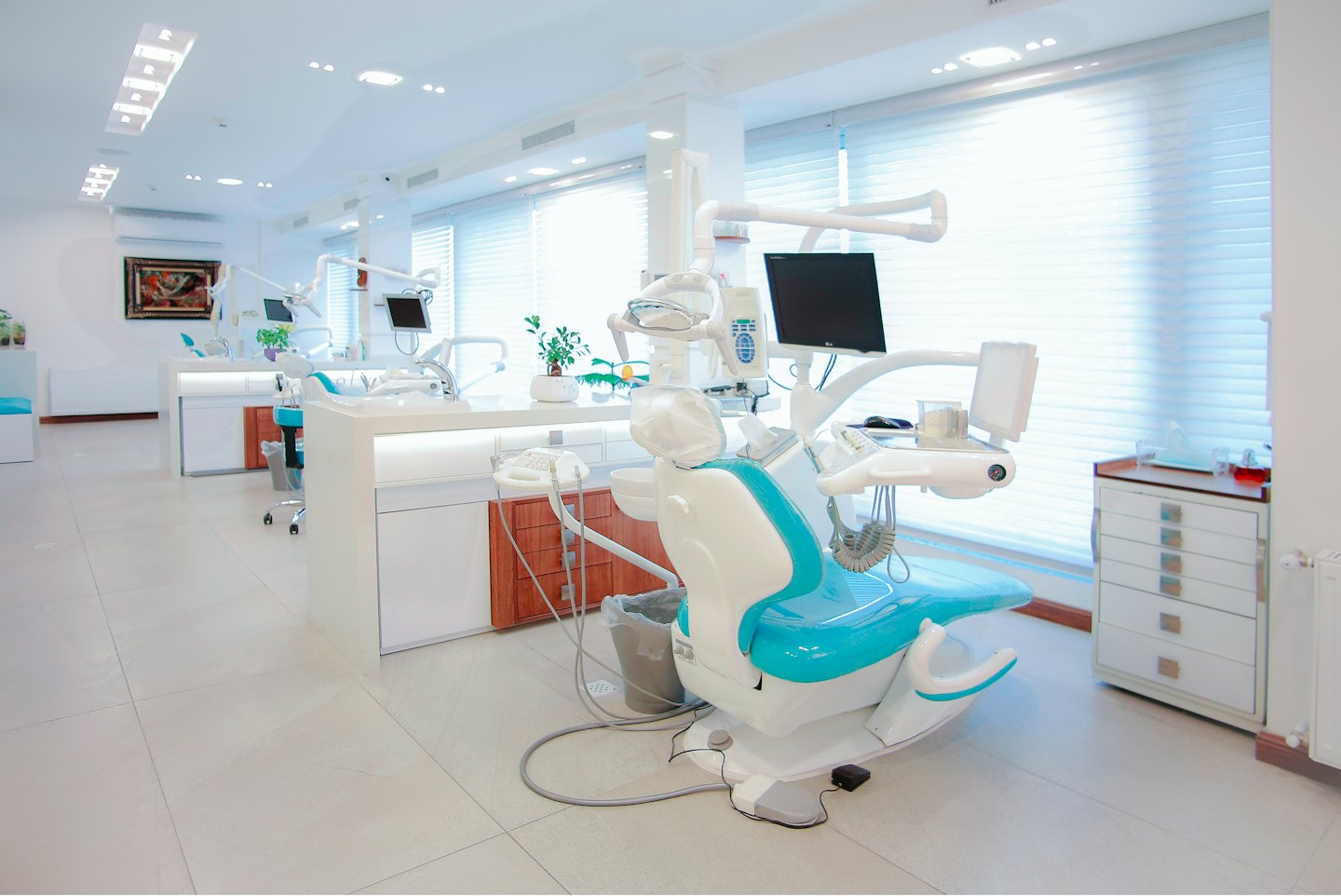 Interior de clínica dental moderna con sillas turquesas y blancas.